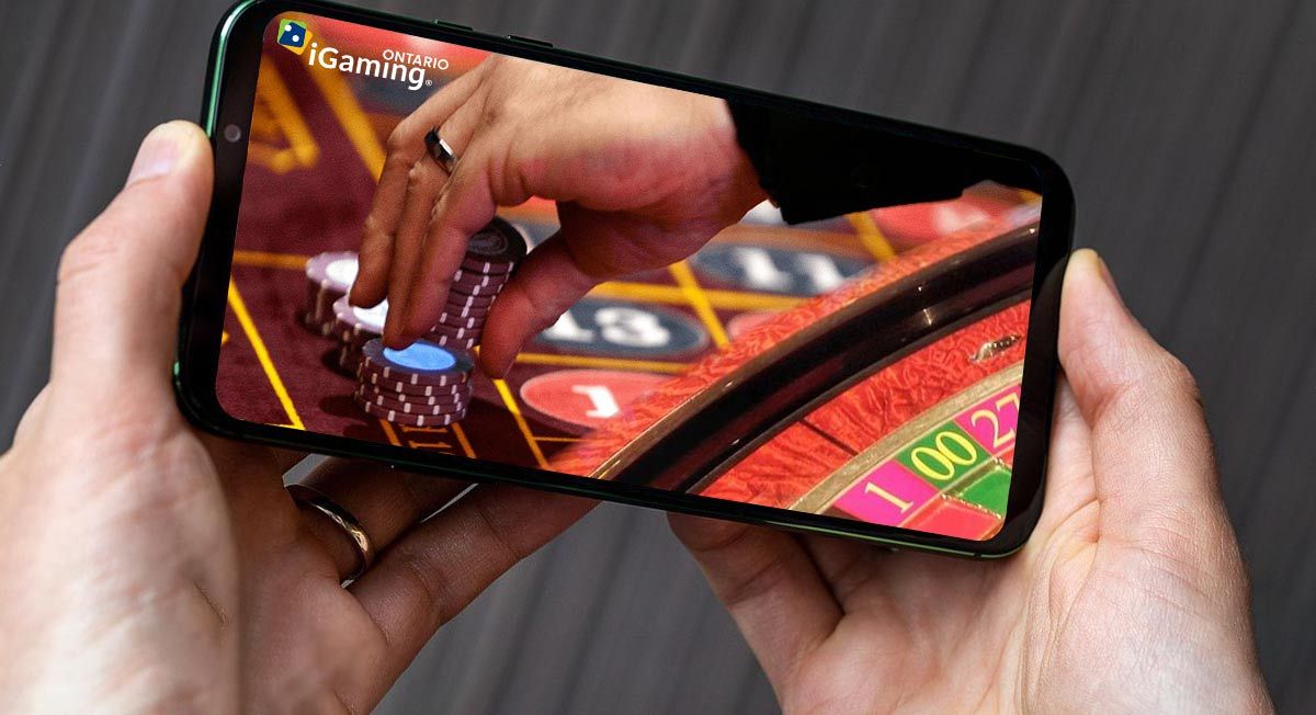 A man holds a phone in his hands with an online casino displayed